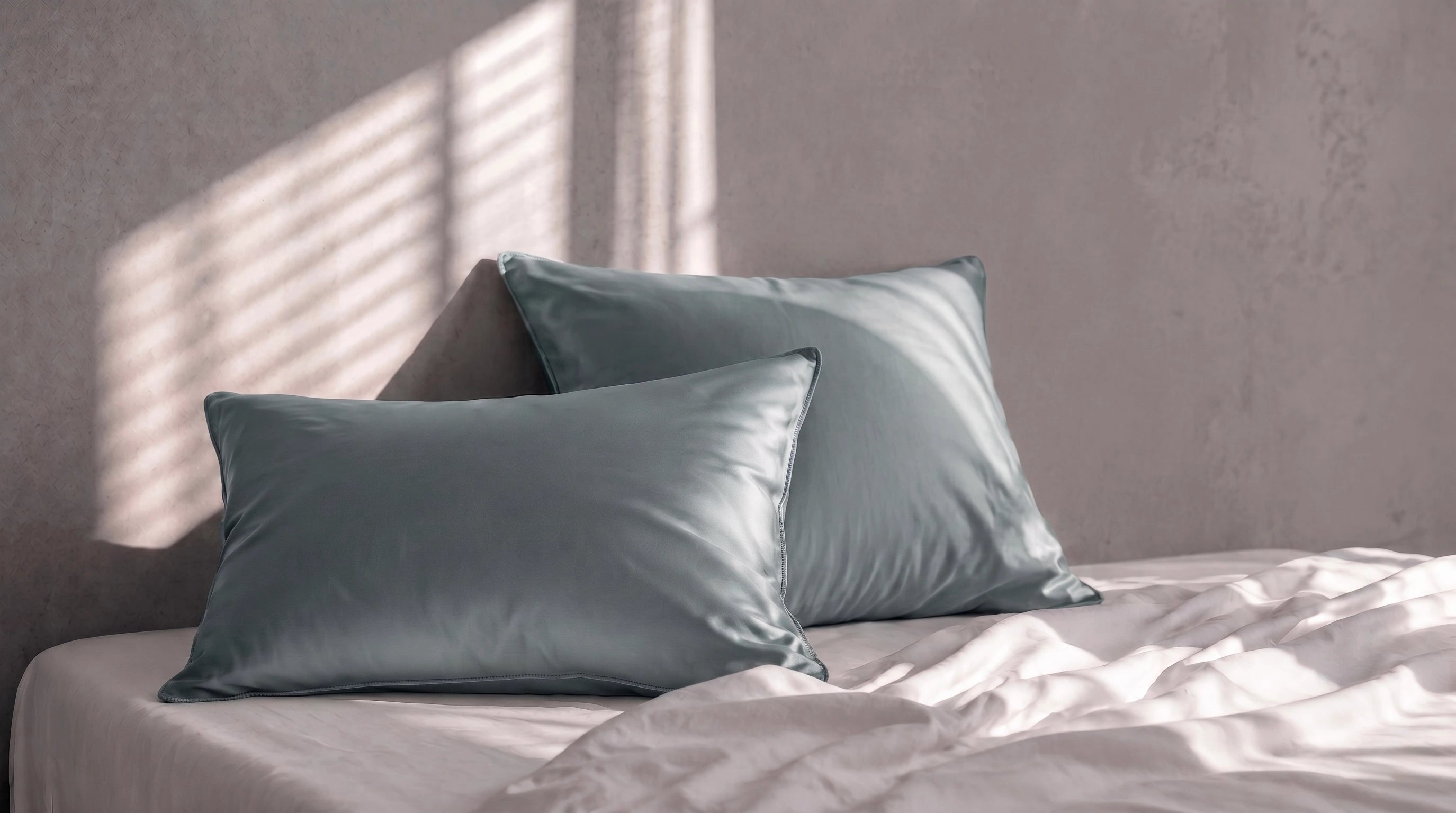 2 taie verte superposé sur fond gris et un lit blanc.