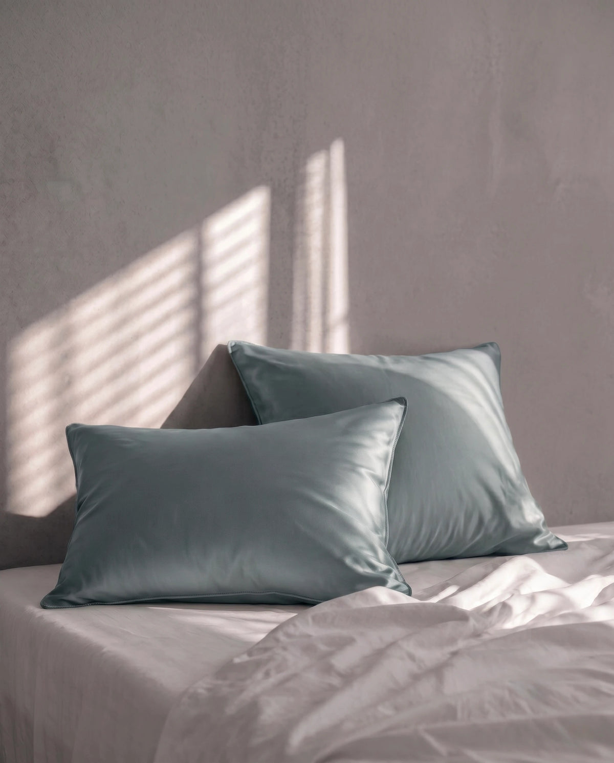 2 taie verte superposé sur fond gris et un lit blanc.