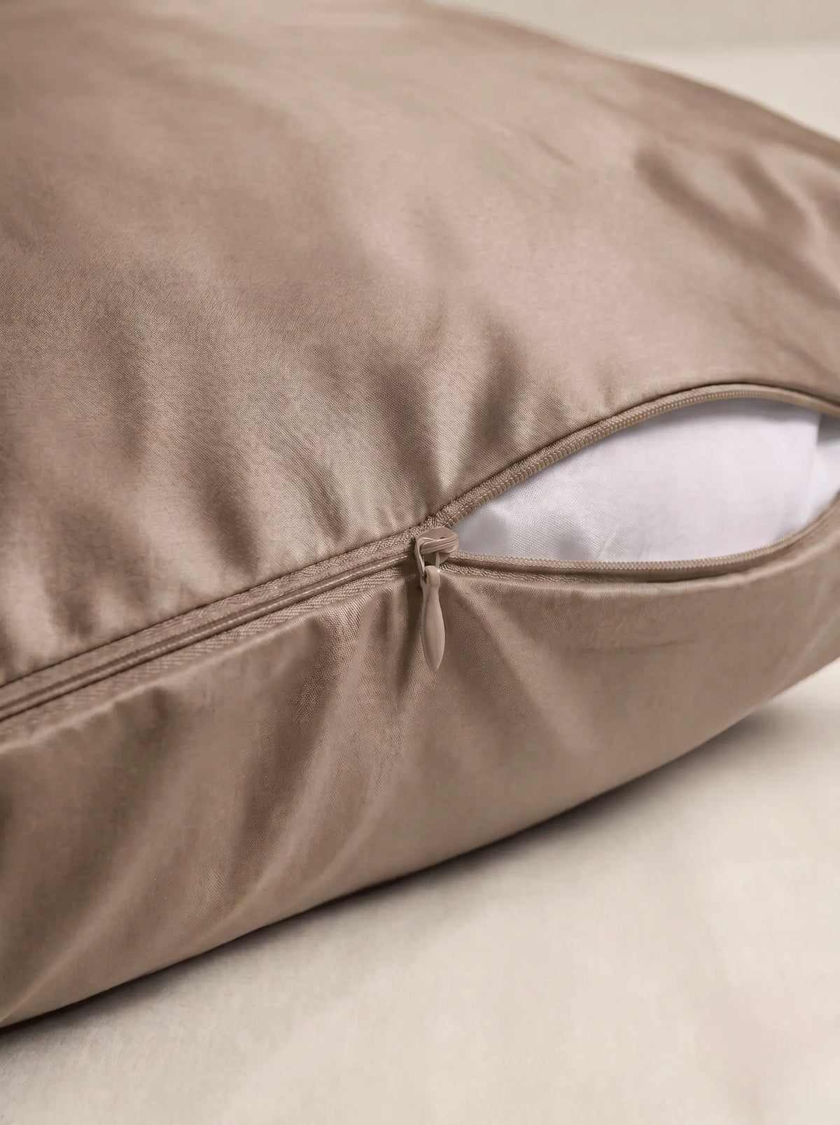 Taie d'oreiller en soie 19 mommes beige, zoom sur les détails de la fermeture éclair, sur fond ivoire.