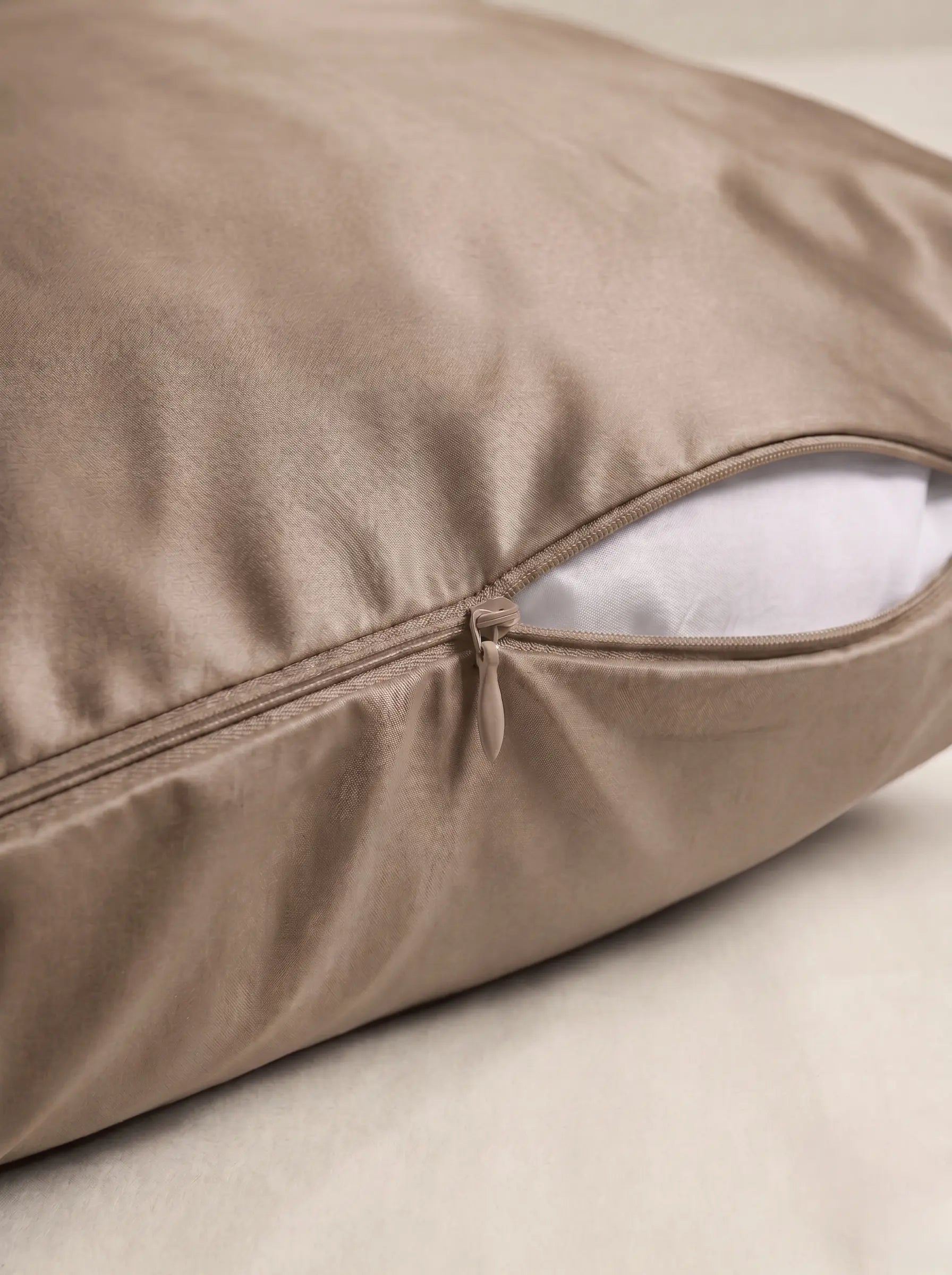 Taie d'oreiller en soie 19 mommes beige, zoom sur les détails de la fermeture éclair, sur fond ivoire.