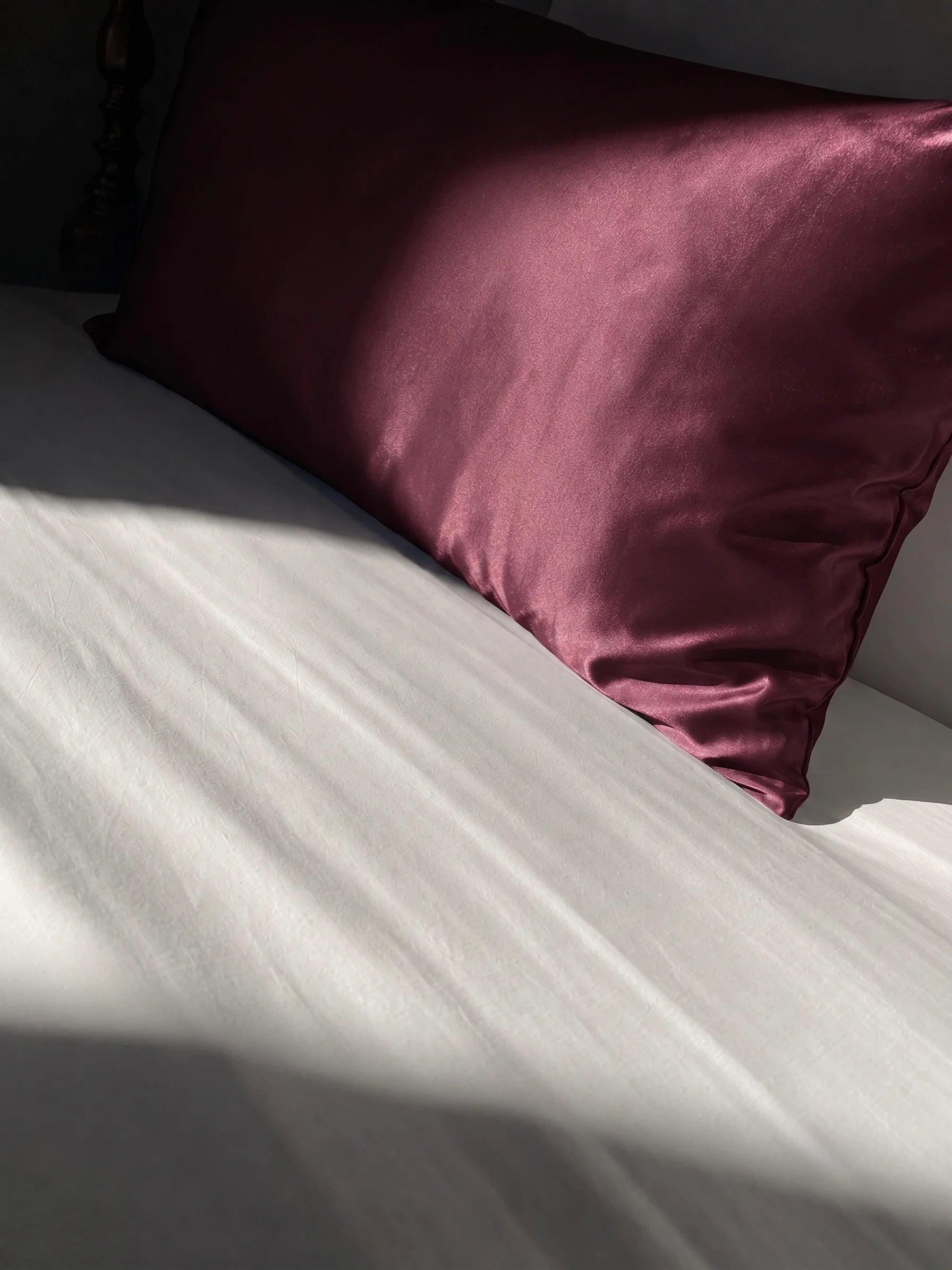Taie d'oreiller en soie 22 mommes rouge sur lit blanc.