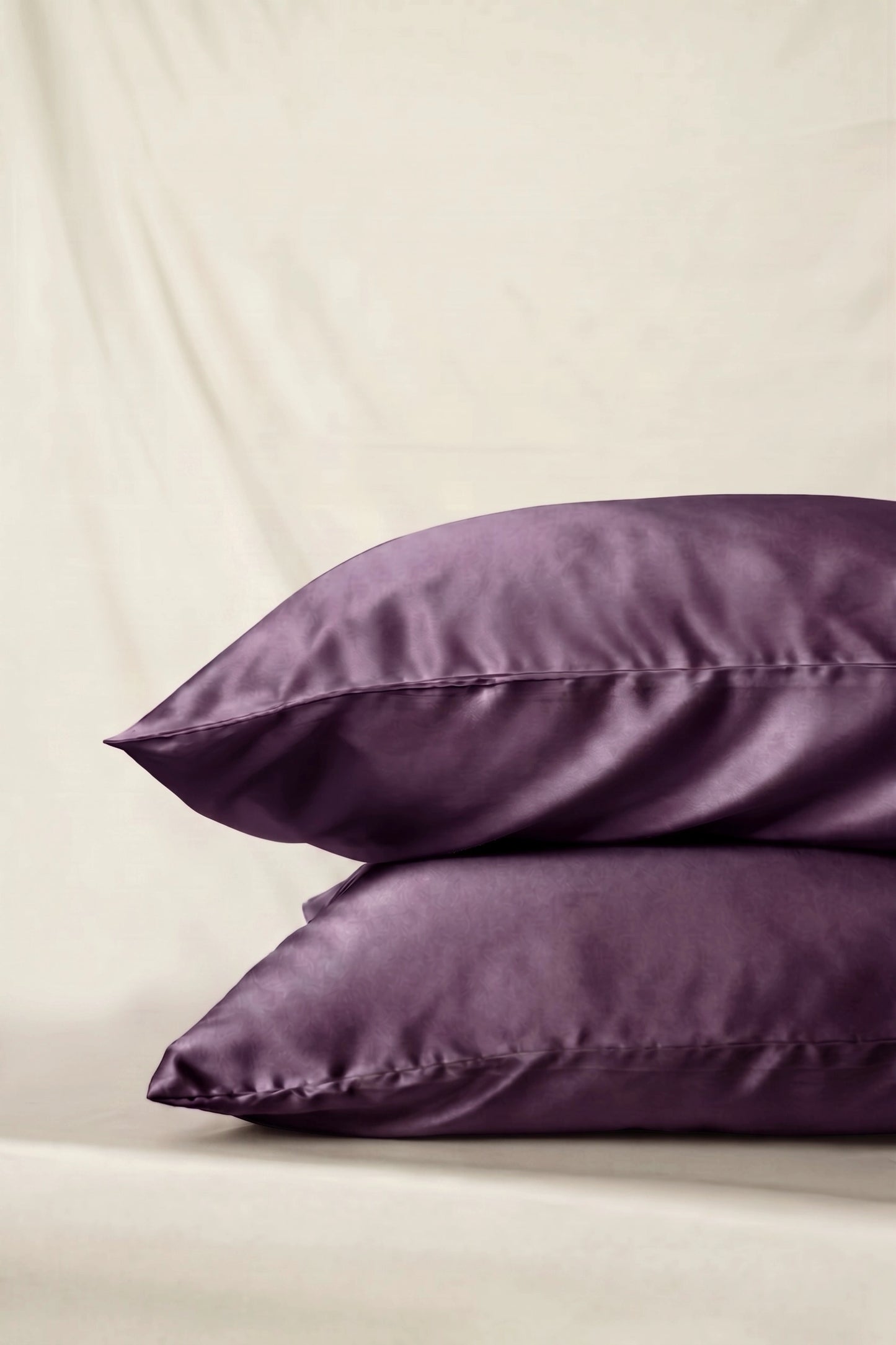 Taie d'oreiller en soie 22 mommes violette empilé sur fond ivoire.