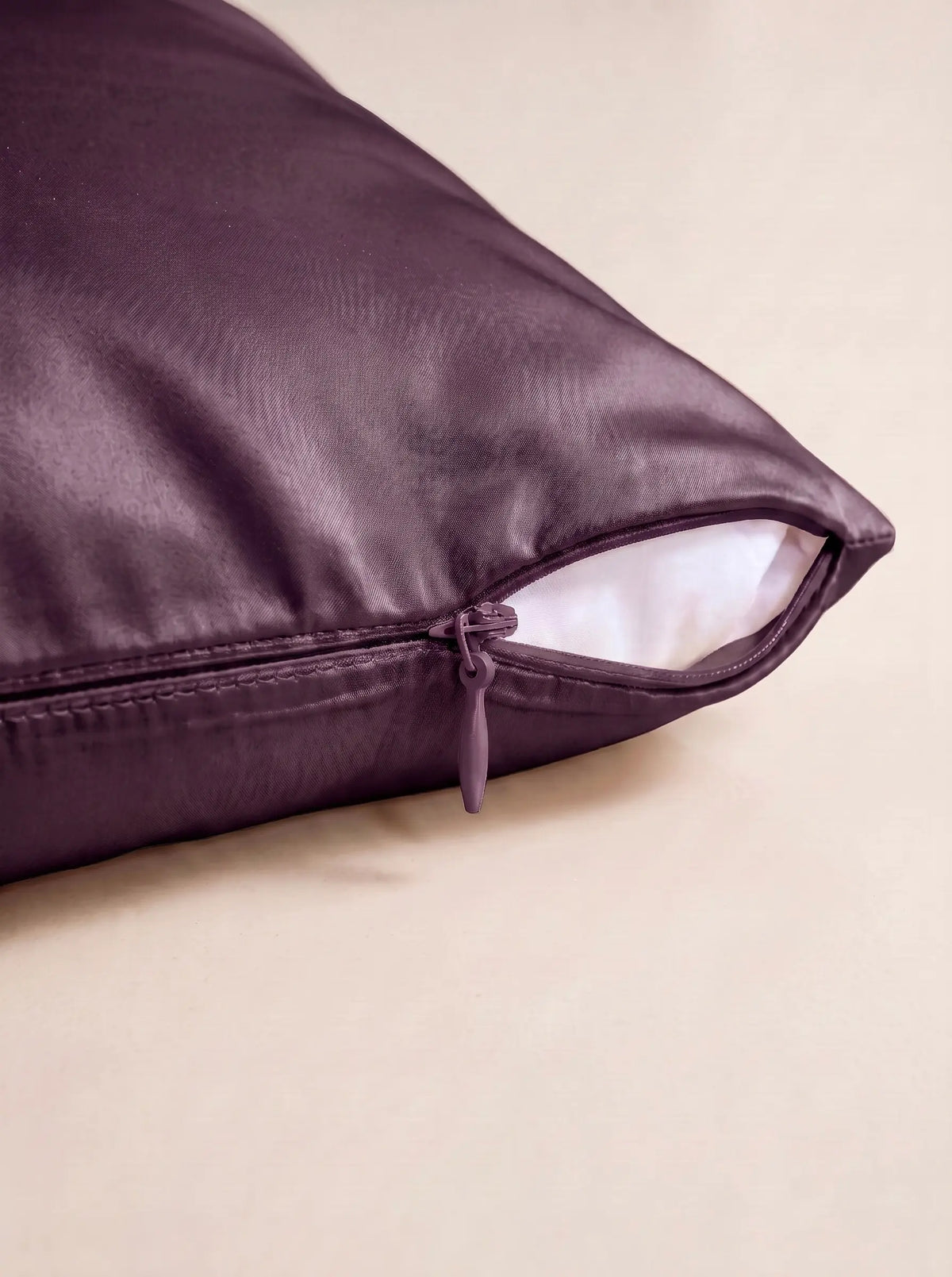 Taie d'oreiller en soie 22 mommes violette, zoom sur les détails de la fermeture éclair, sur fond ivoire.