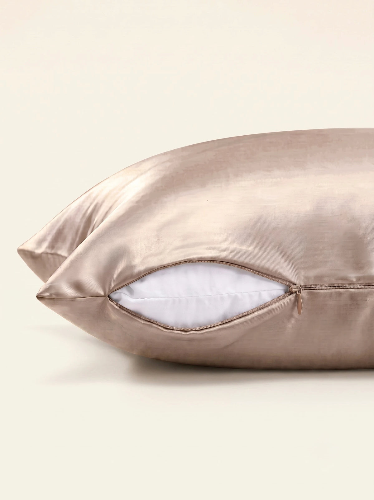 Taie d'oreiller en soie 25 mommes ivoire, zoom sur les détails de la fermeture éclair, sur fond beige.