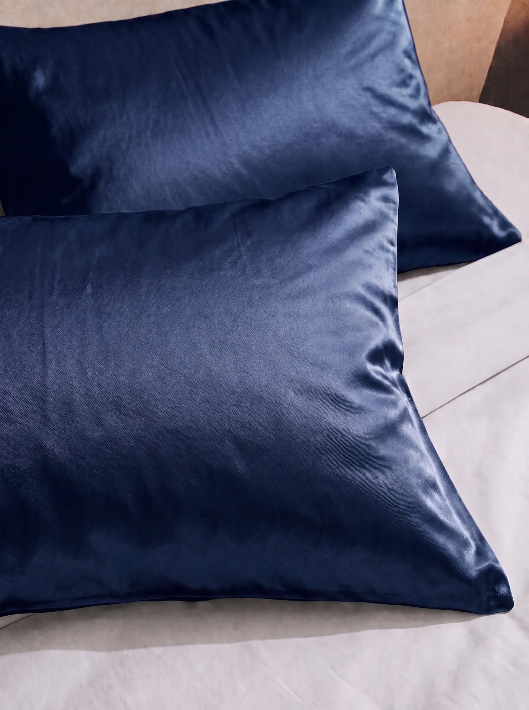2 taie d'oreiller en soie 25 mommes bleu marine sur lit blanc.