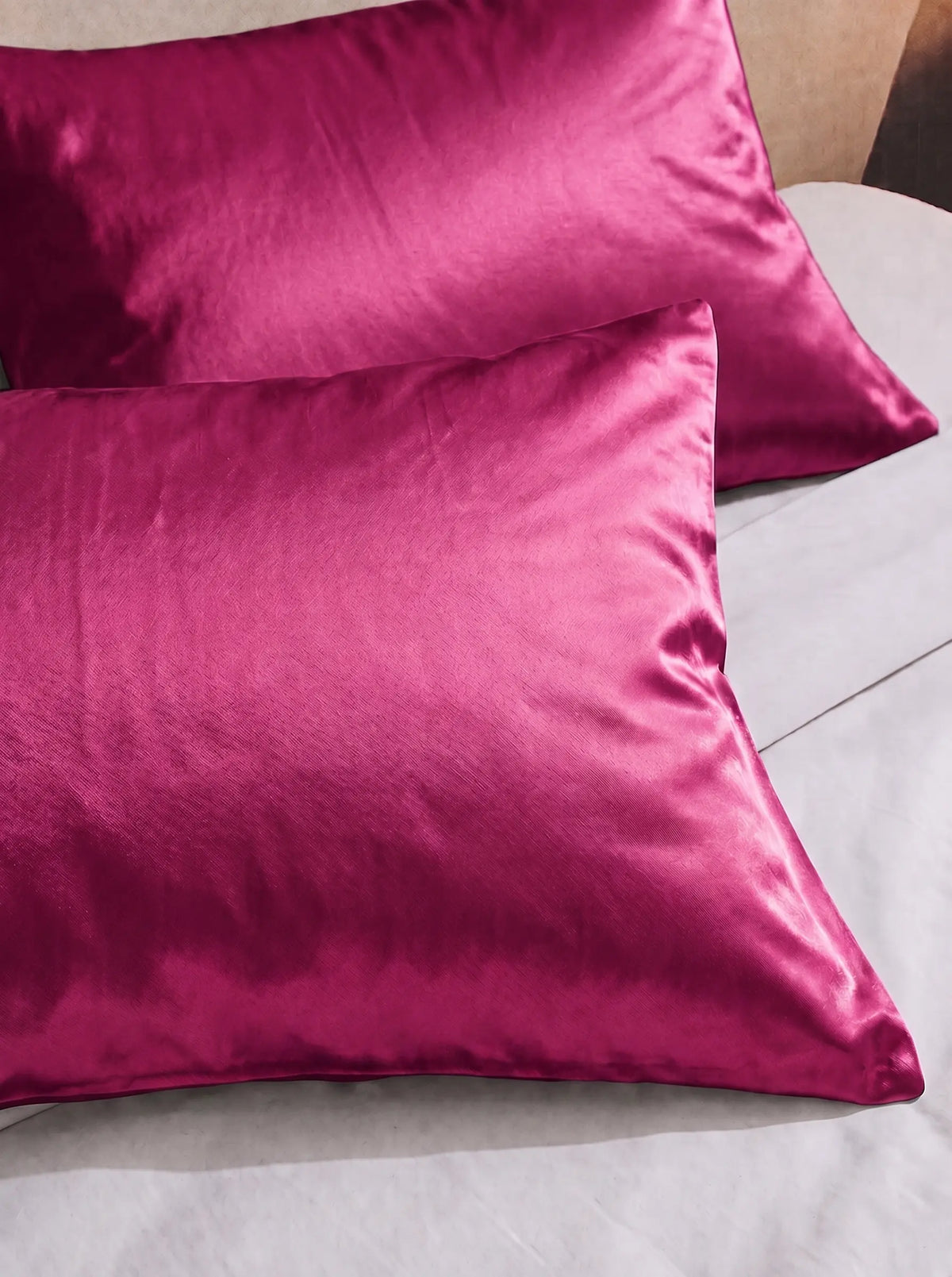 2 taie d'oreiller en soie 25 mommes fuchsia sur lit blanc.