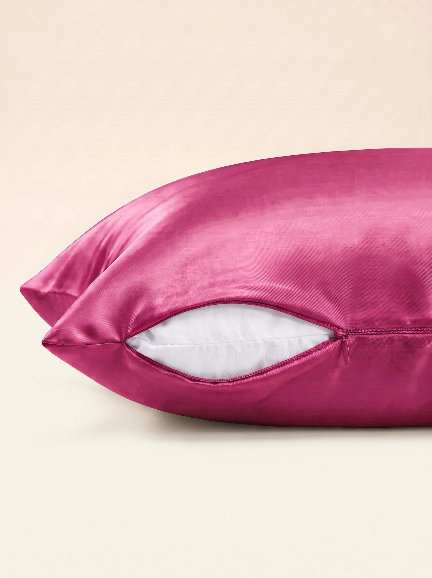 Taie d'oreiller en soie 25 mommes fuchsia, zoom sur les détails de la fermeture éclair, sur fond ivoire.