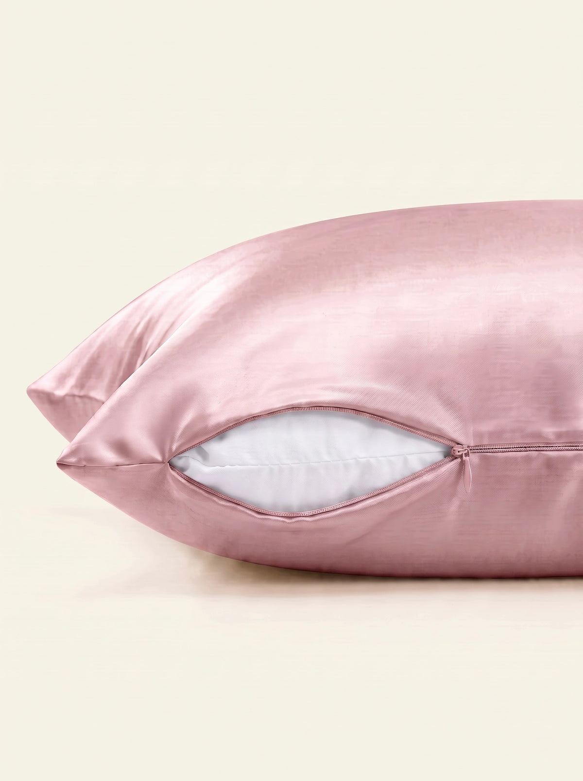 Taie d'oreiller en soie 25 mommes ivoire, zoom sur les détails de la fermeture éclair, sur fond rose.