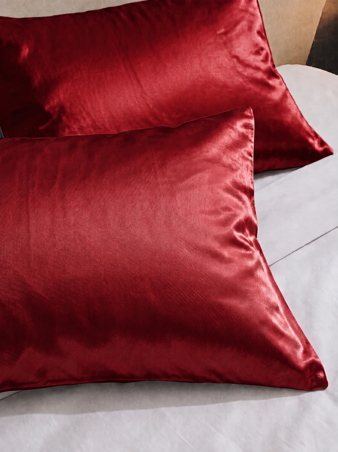 2 taie d'oreiller en soie 25 mommes rouge sur lit blanc.