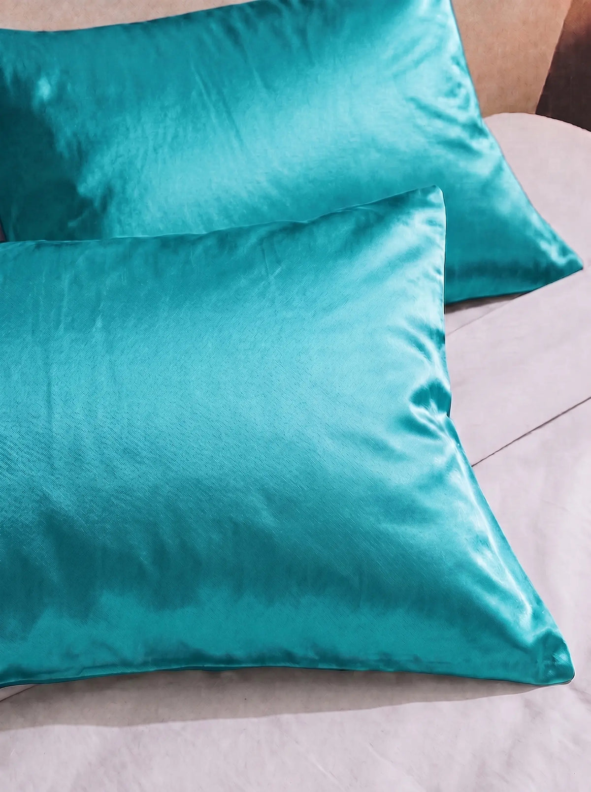 2 taie d'oreiller en soie 25 mommes turquoise sur lit blanc.