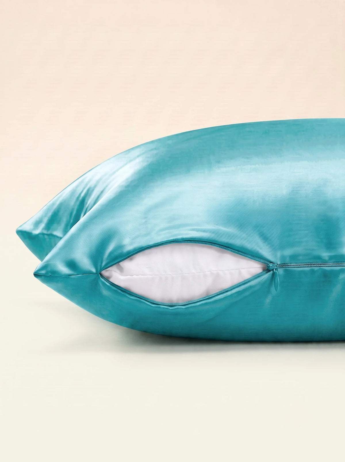 Taie d'oreiller en soie 25 mommes turquoise, zoom sur les détails de la fermeture éclair, sur fond ivoire.