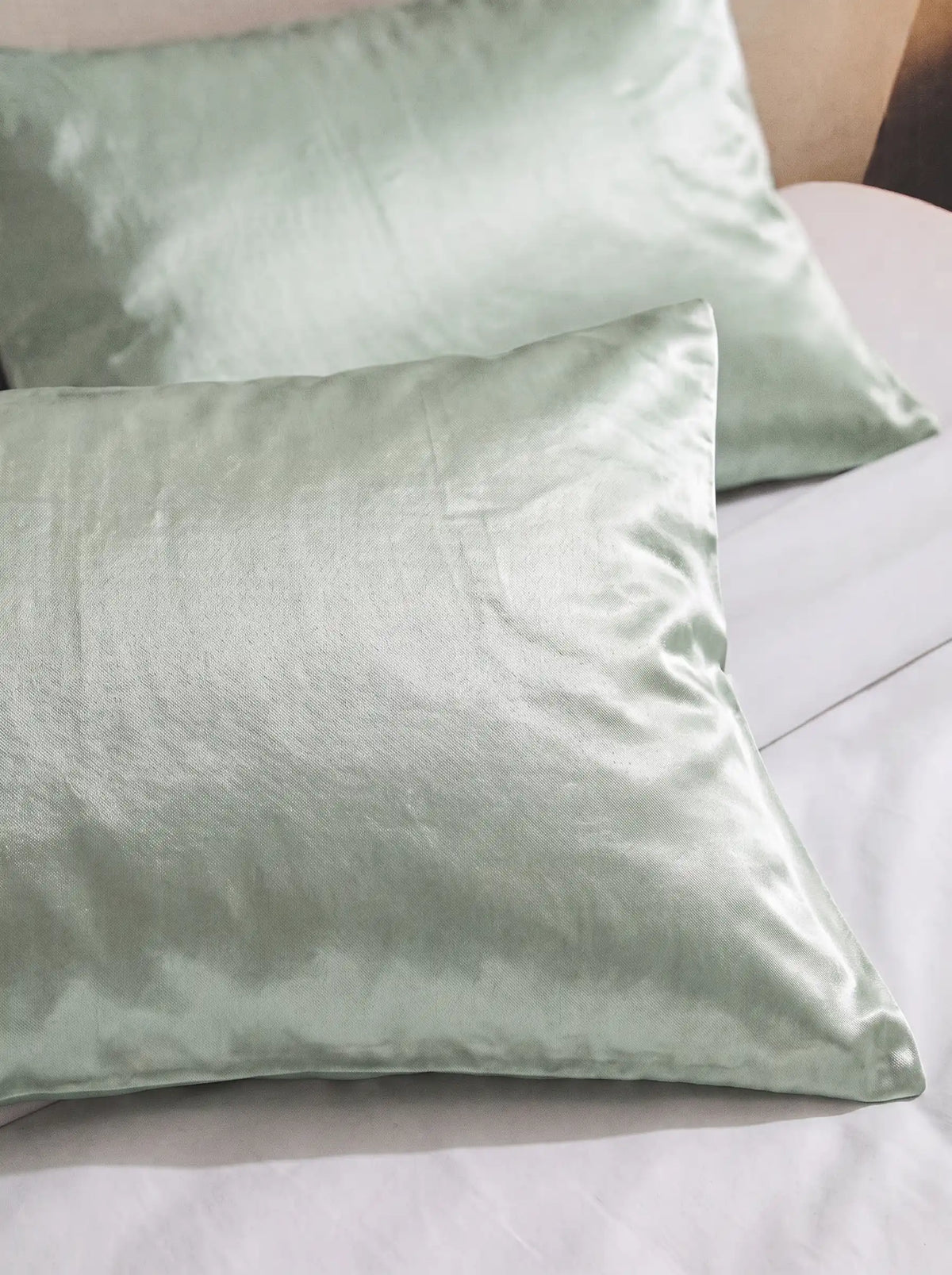 2 taie d'oreiller en soie 25 mommes verte pâle sur lit blanc.