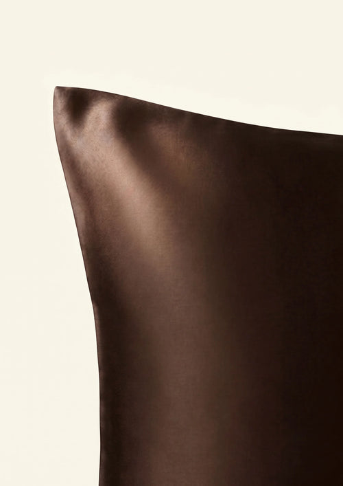 Bord d'une taie marron chocolat sur fond ivoire.